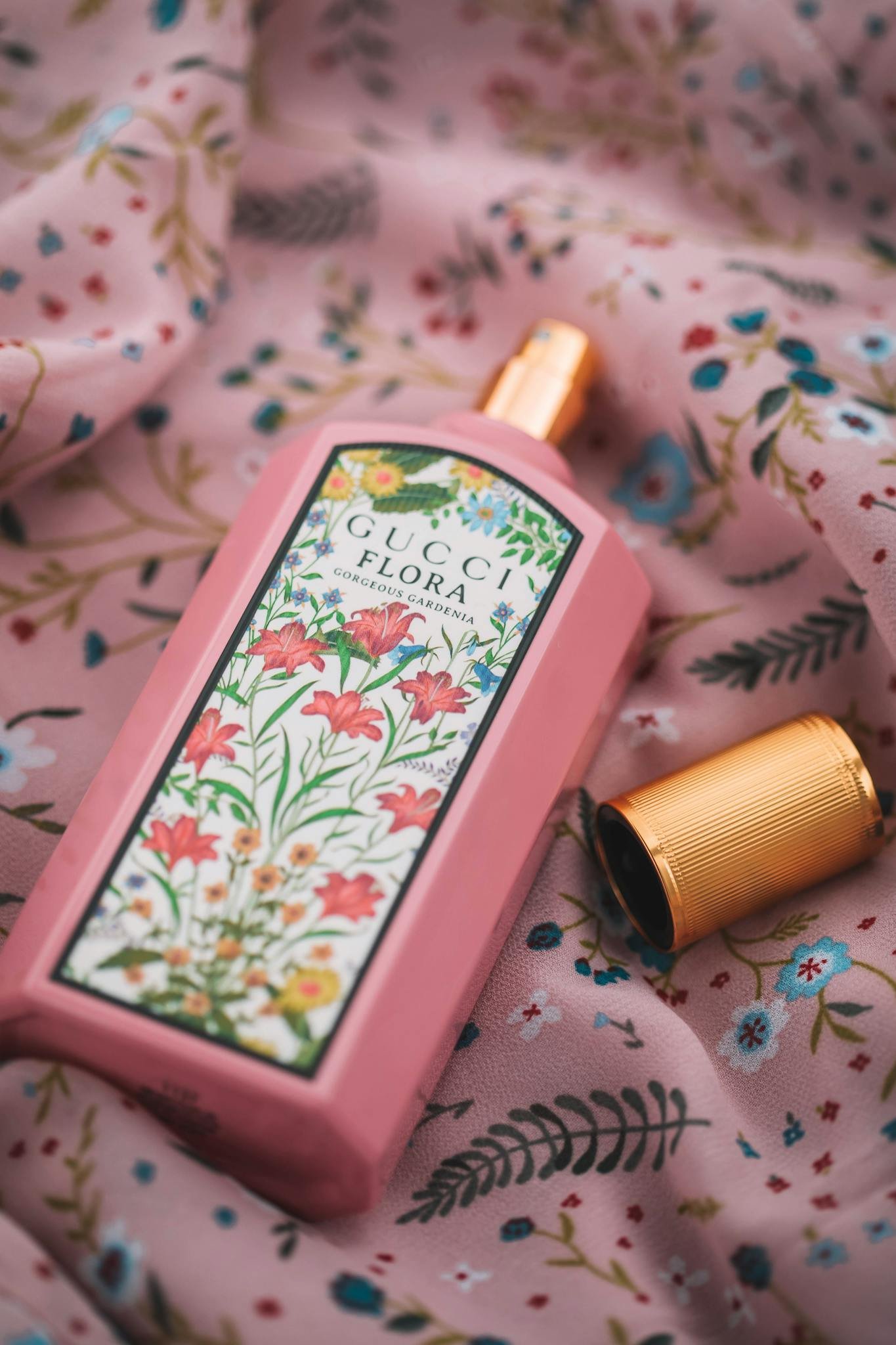 A stylish Gucci Flora perfume bottle on floral fabric, showcasing luxury and elegance.