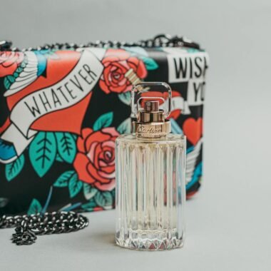 Stylish Cartier perfume bottle and colorful designer bag in a chic flatlay setting.